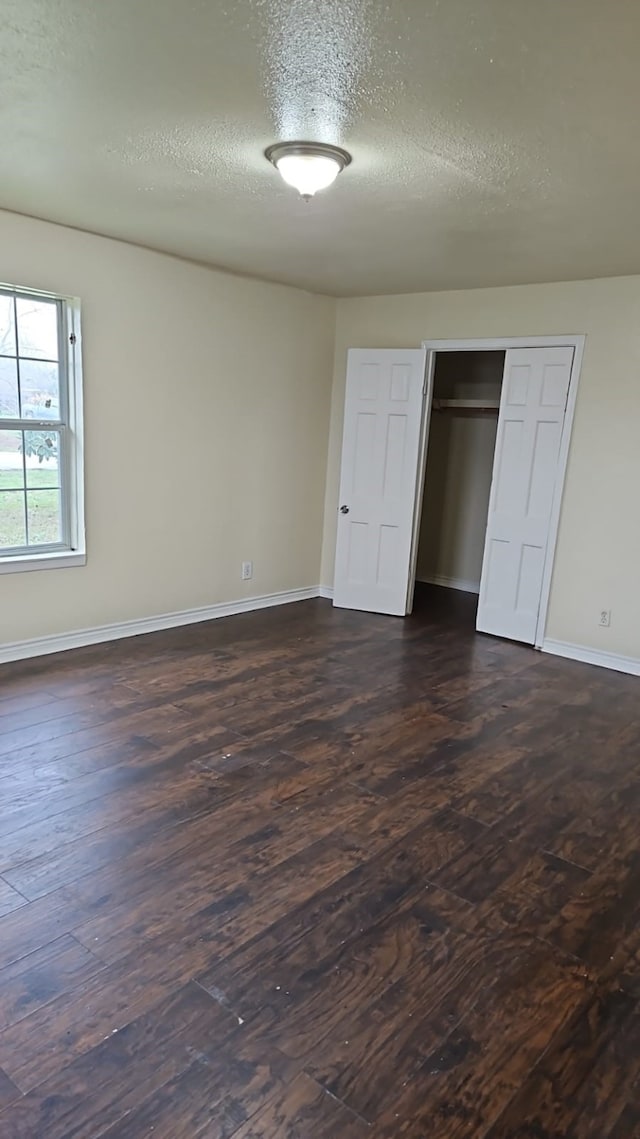 unfurnished bedroom featuring a closet, dark hardwood / wood-style flooring, and a textured ceiling