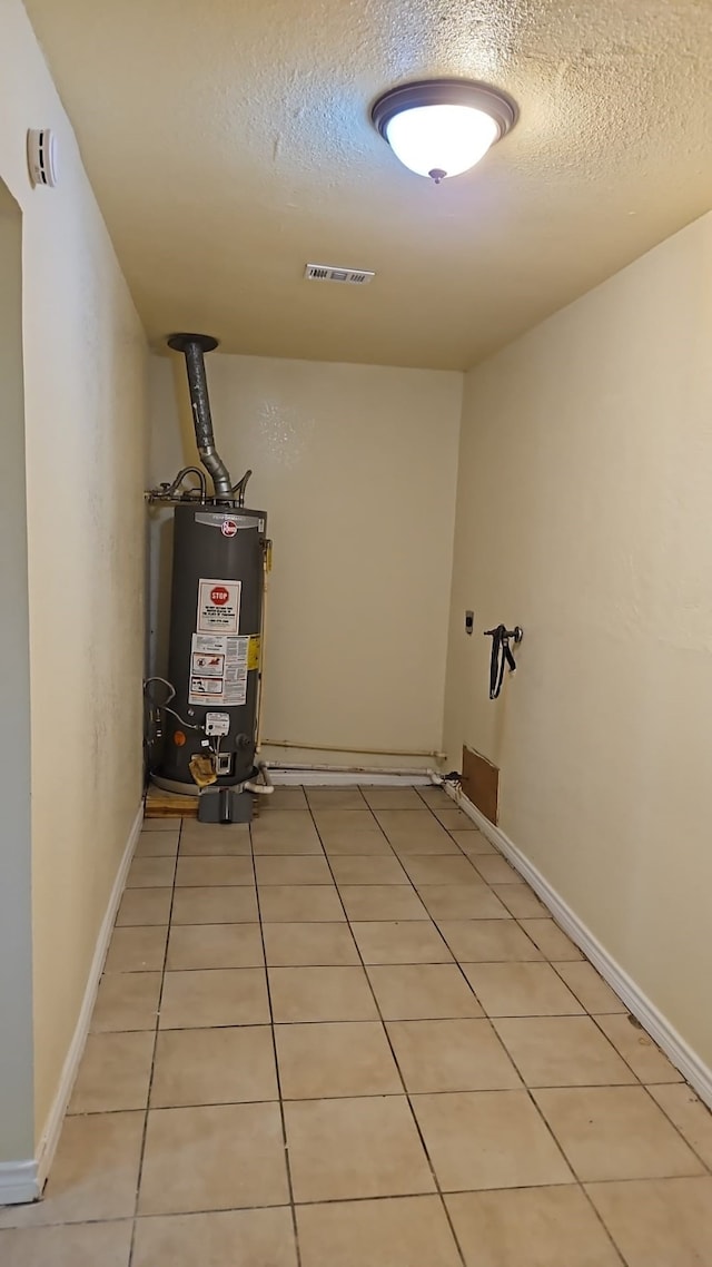 interior space with gas water heater, light tile patterned flooring, and a textured ceiling