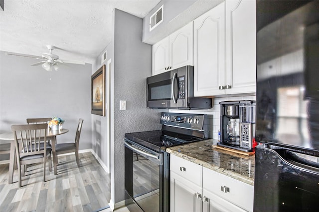 1505 Ward Rd Unit 232, Baytown, TX 77520 - kitchen with electric stove, stainless steel microwave, freestanding refrigerator, a ceiling fan, and white cabinetry