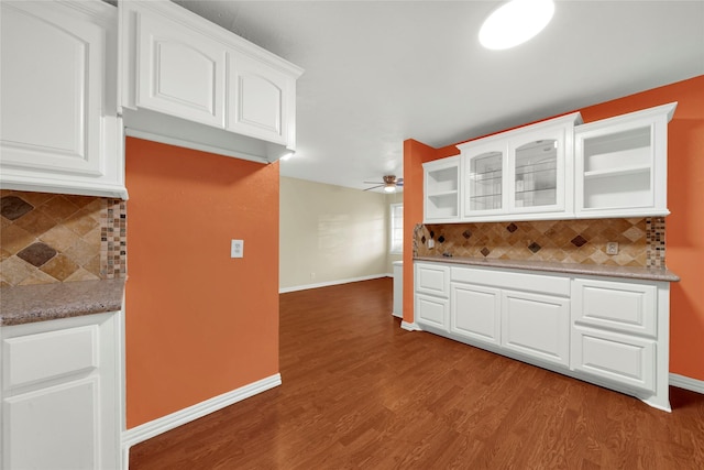 kitchen featuring hardwood / wood-style flooring, ceiling fan, tasteful backsplash, light stone countertops, and white cabinets