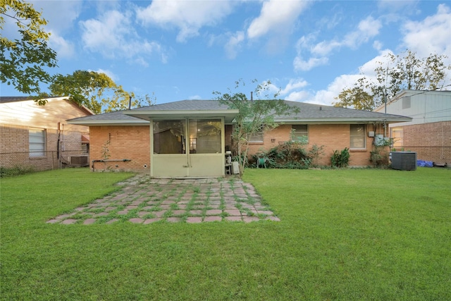 back of property featuring a patio, a sunroom, a lawn, and central air condition unit