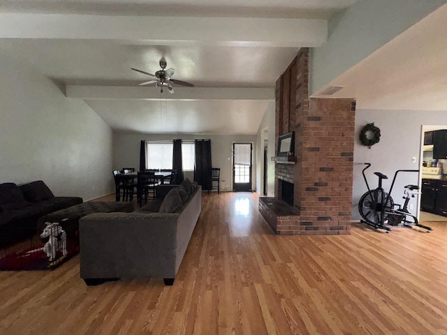 living room with a brick fireplace, hardwood / wood-style flooring, lofted ceiling with beams, and ceiling fan