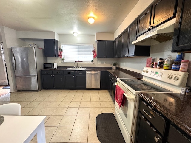 kitchen featuring sink, light tile patterned floors, stainless steel appliances, and a textured ceiling