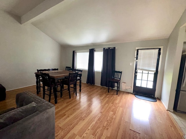 dining room featuring vaulted ceiling with beams and light hardwood / wood-style floors