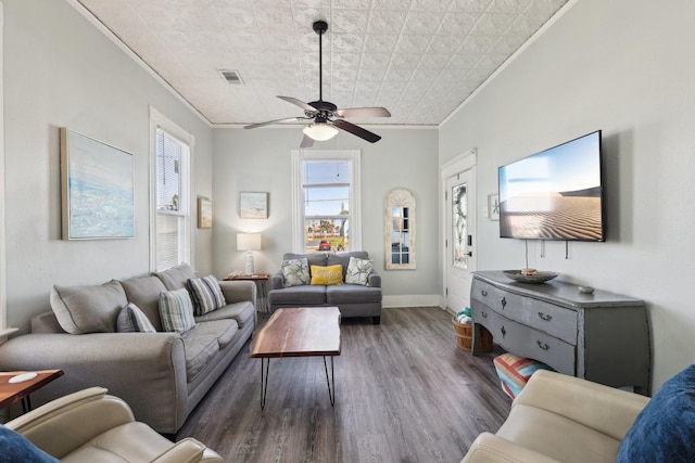 living area featuring ceiling fan, wood finished floors, visible vents, baseboards, and crown molding