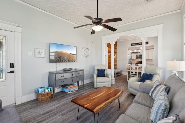 living room featuring ornamental molding, ornate columns, baseboards, and wood finished floors