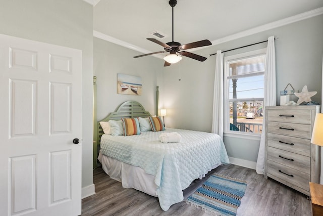 bedroom with crown molding, visible vents, a ceiling fan, wood finished floors, and baseboards