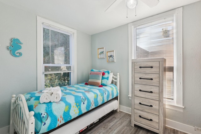 bedroom with multiple windows, baseboards, and wood finished floors