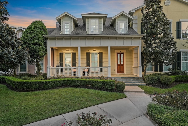 new england style home featuring a yard and a porch