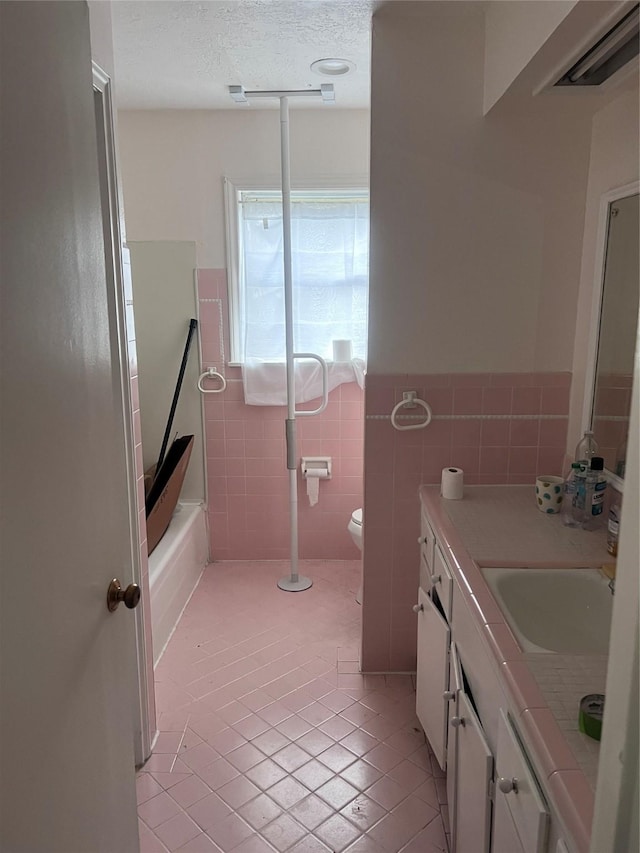 full bathroom with toilet, tub / shower combination, a textured ceiling, tile walls, and vanity