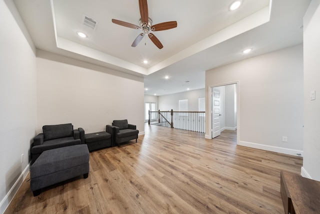 sitting room with a raised ceiling, ceiling fan, and light hardwood / wood-style floors