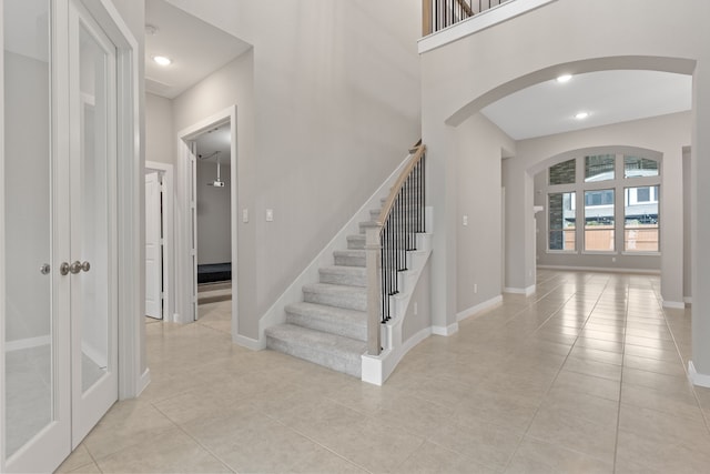 tiled entryway with arched walkways, baseboards, and recessed lighting