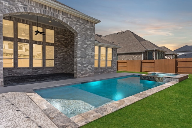 view of pool featuring a pool with connected hot tub, fence, a lawn, and a patio