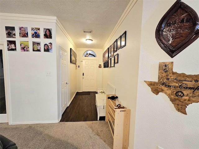 hallway with crown molding, a textured ceiling, and dark colored carpet