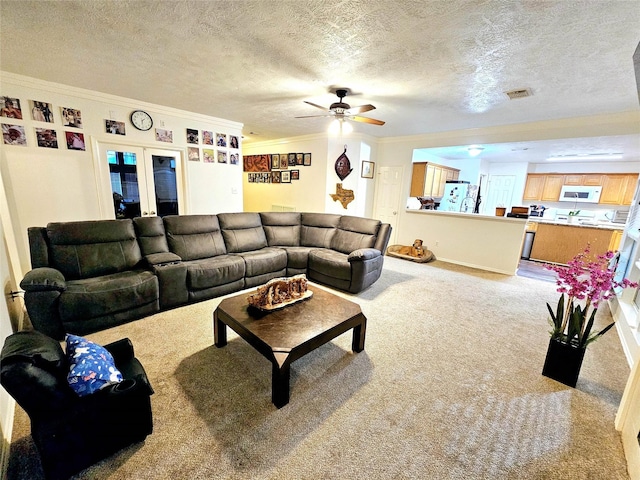 living room featuring crown molding, carpet flooring, ceiling fan, and a textured ceiling