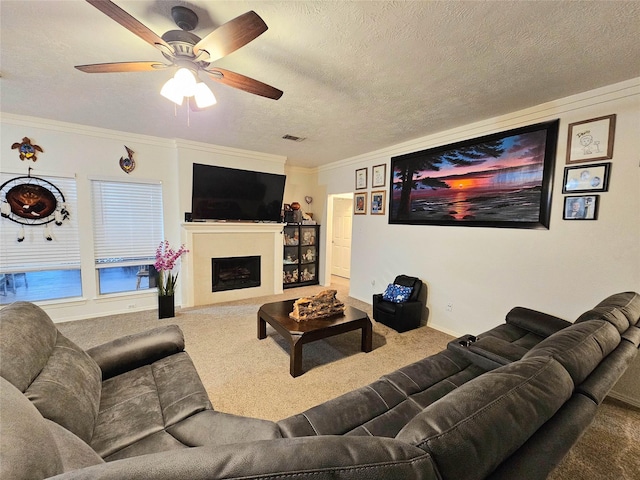 living room with ceiling fan, ornamental molding, a textured ceiling, and carpet flooring