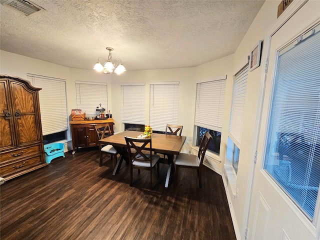 dining area with dark wood-type flooring, an inviting chandelier, and a textured ceiling