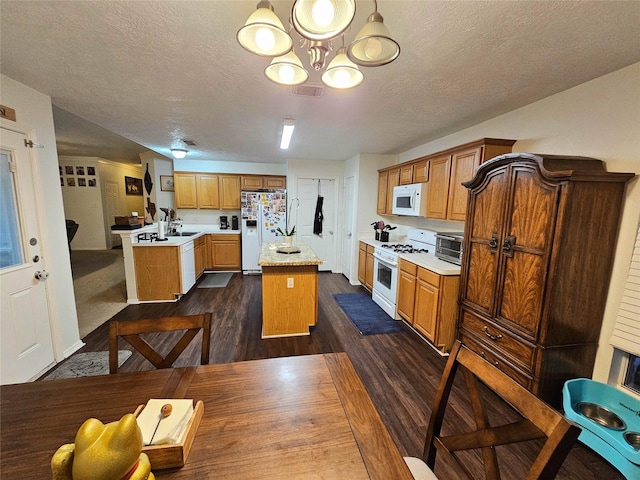 kitchen with a chandelier, hanging light fixtures, dark hardwood / wood-style floors, an island with sink, and white appliances