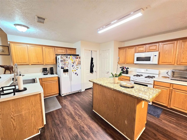 kitchen featuring a kitchen island, sink, dark wood-type flooring, and white appliances