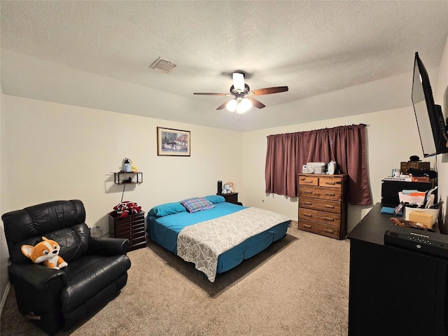 bedroom featuring ceiling fan, carpet floors, and a textured ceiling