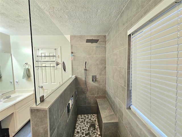 bathroom with vanity, a tile shower, and a textured ceiling