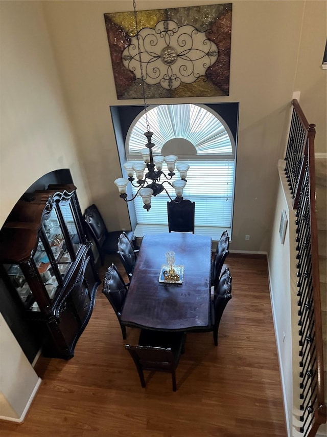 dining area with baseboards, stairway, wood finished floors, and a notable chandelier