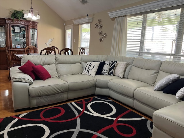 living area with wood finished floors, visible vents, vaulted ceiling, and an inviting chandelier