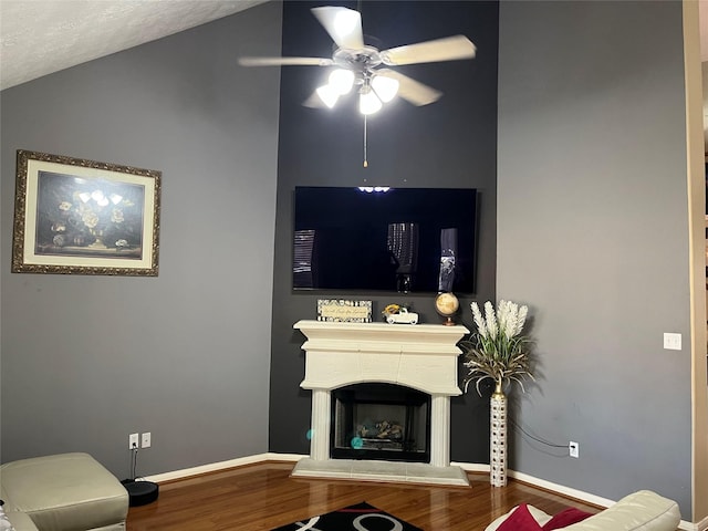 living room featuring a fireplace with raised hearth, vaulted ceiling, baseboards, and wood finished floors
