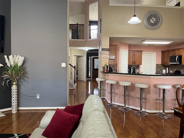kitchen with decorative light fixtures, dark countertops, stainless steel microwave, brown cabinetry, and a peninsula