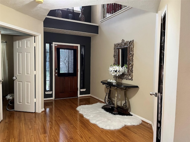 entrance foyer featuring a textured ceiling, wood finished floors, and baseboards