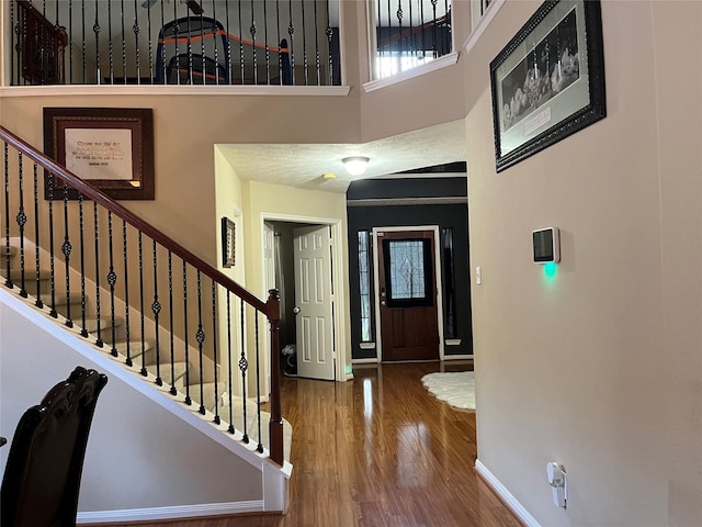 foyer entrance featuring a high ceiling, stairway, wood finished floors, and baseboards