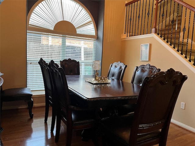 dining area featuring stairs, baseboards, and wood finished floors