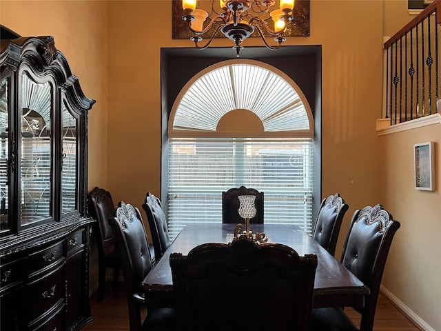 dining area featuring wood finished floors, baseboards, and an inviting chandelier