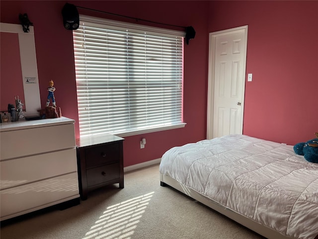 bedroom featuring light carpet and baseboards