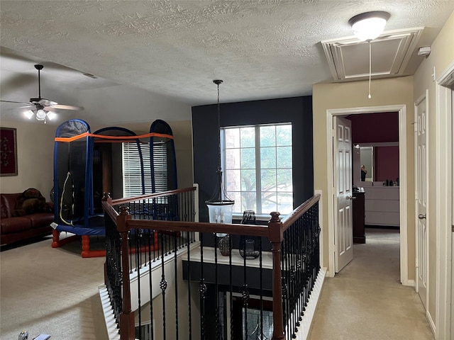 interior space with attic access, light carpet, and a textured ceiling