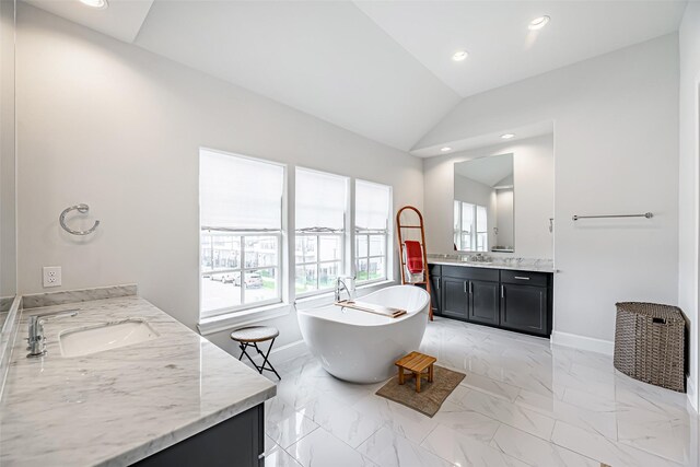 bathroom featuring vanity, lofted ceiling, and a bath