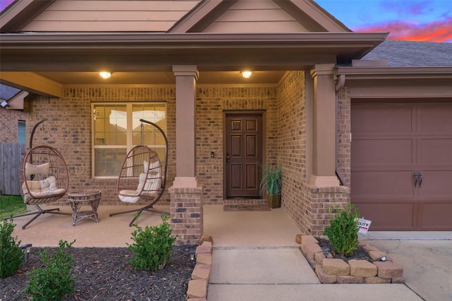 exterior entry at dusk with a garage and covered porch