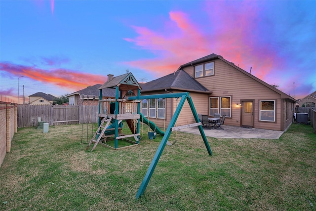 playground at dusk featuring a patio and a lawn