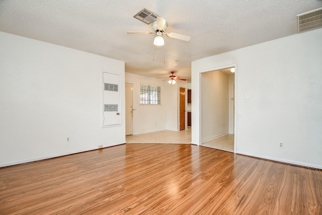 spare room with ceiling fan, a textured ceiling, and light wood-type flooring