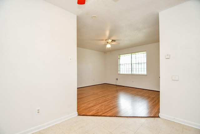 spare room with ceiling fan, light hardwood / wood-style flooring, and a textured ceiling