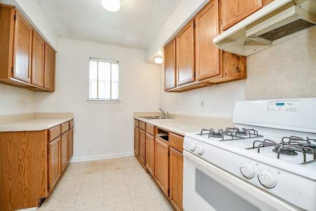 kitchen with white gas range, sink, and a textured ceiling