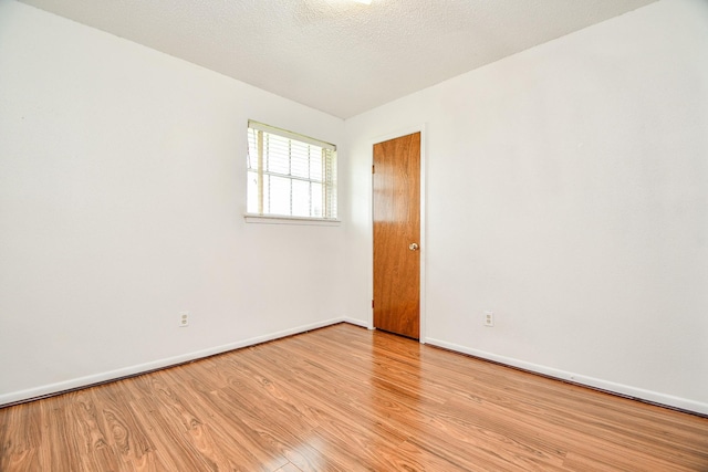 empty room featuring a textured ceiling and light hardwood / wood-style flooring