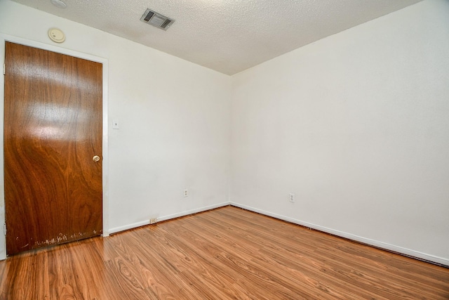 spare room with hardwood / wood-style floors and a textured ceiling