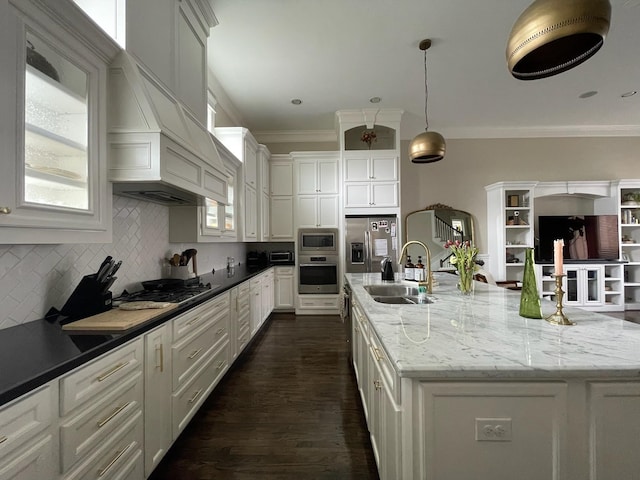 kitchen with sink, hanging light fixtures, dark stone countertops, appliances with stainless steel finishes, and a large island