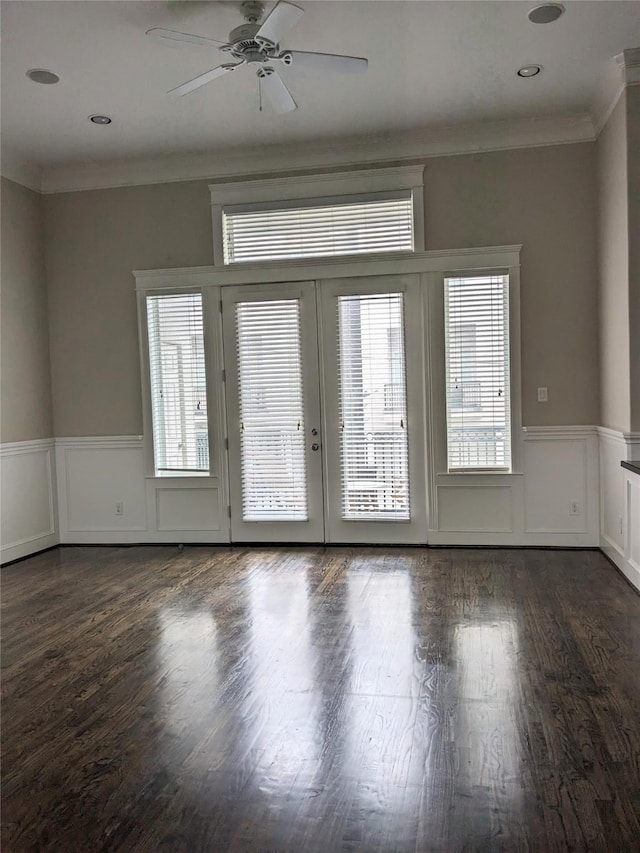 spare room featuring ornamental molding, a healthy amount of sunlight, ceiling fan, and dark hardwood / wood-style flooring