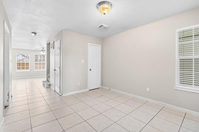 spare room featuring baseboards, ceiling fan, visible vents, and light tile patterned flooring