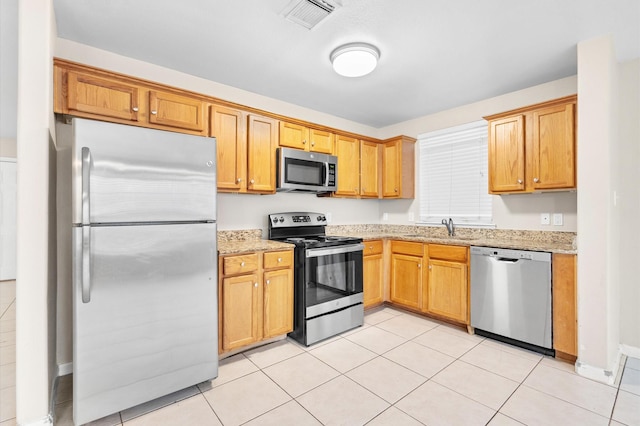 kitchen featuring a sink, light tile patterned floors, visible vents, light stone counters, and stainless steel appliances