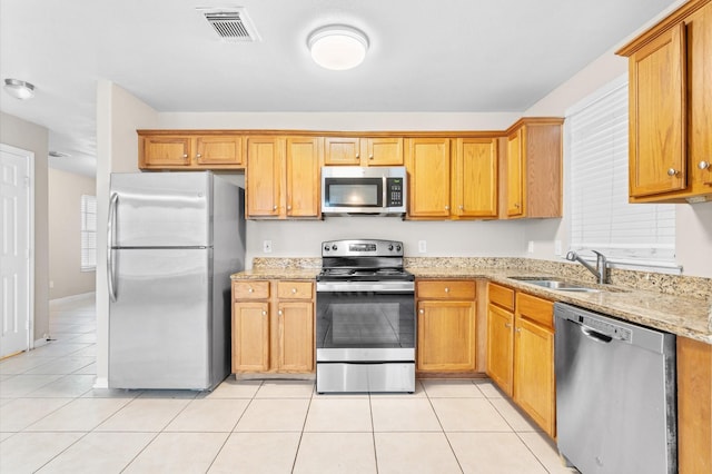 kitchen featuring visible vents, light stone counters, a sink, light tile patterned floors, and appliances with stainless steel finishes