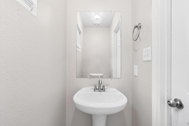 half bath with a sink and a textured wall