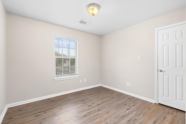 spare room with baseboards, visible vents, and wood finished floors